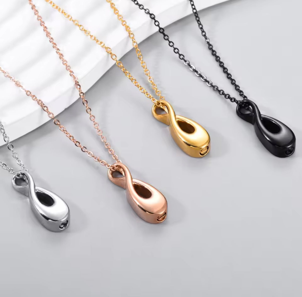 Four necklaces with different colored pendants on a light gray background